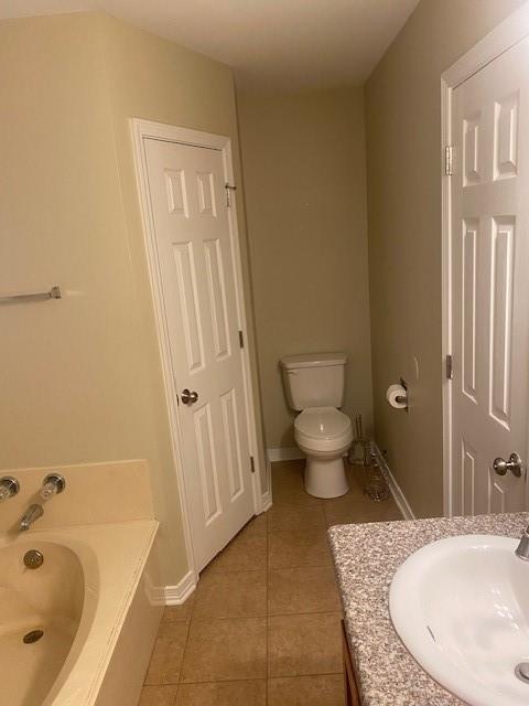 bathroom with vanity, toilet, tile floors, and a tub