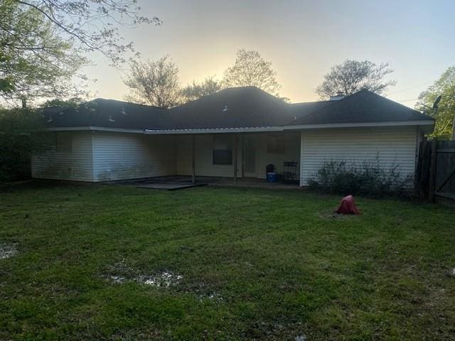 back house at dusk featuring a yard