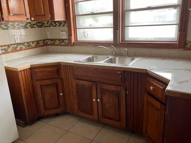 kitchen with a healthy amount of sunlight, backsplash, light tile patterned flooring, and sink