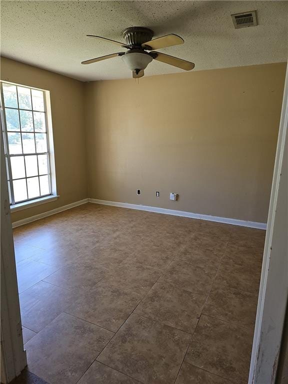 tiled empty room with a textured ceiling and ceiling fan