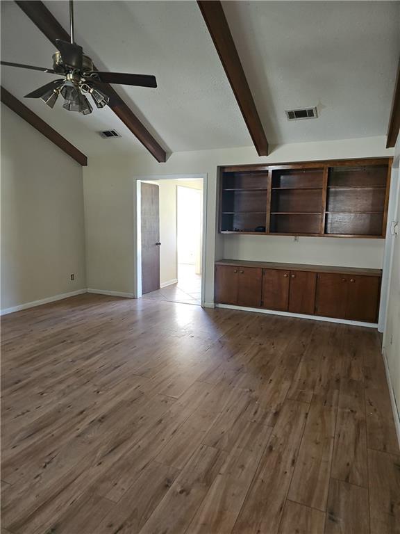 unfurnished living room featuring lofted ceiling with beams, ceiling fan, and hardwood / wood-style floors