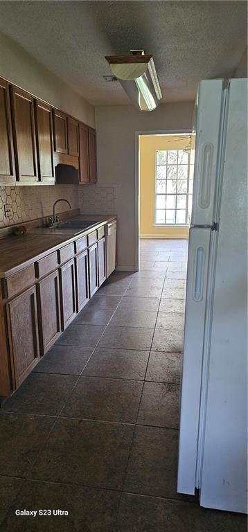 kitchen with tile patterned flooring, tasteful backsplash, and white refrigerator