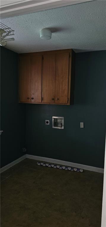 clothes washing area with cabinets, a textured ceiling, tile patterned flooring, and washer hookup