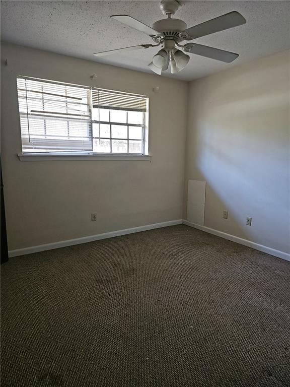 carpeted spare room with a textured ceiling and ceiling fan