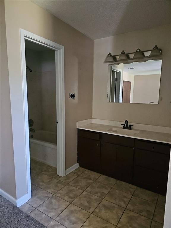 bathroom featuring vanity, tub / shower combination, a textured ceiling, and tile patterned floors