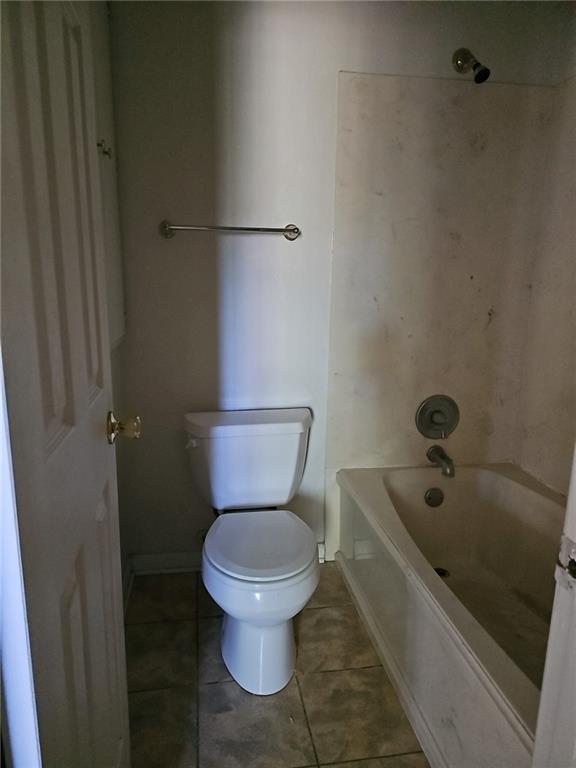 bathroom with toilet, tile patterned floors, and shower / bathing tub combination