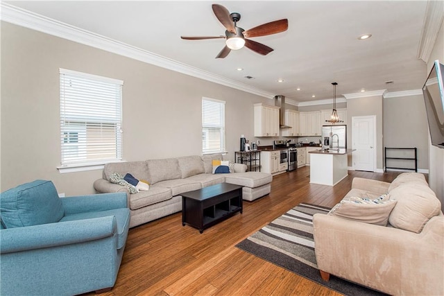 living room featuring ceiling fan, a healthy amount of sunlight, ornamental molding, and wood-type flooring