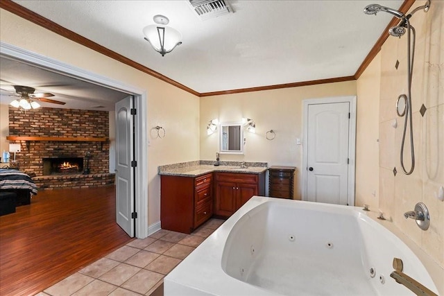 bathroom featuring vanity, ceiling fan, wood-type flooring, a brick fireplace, and crown molding