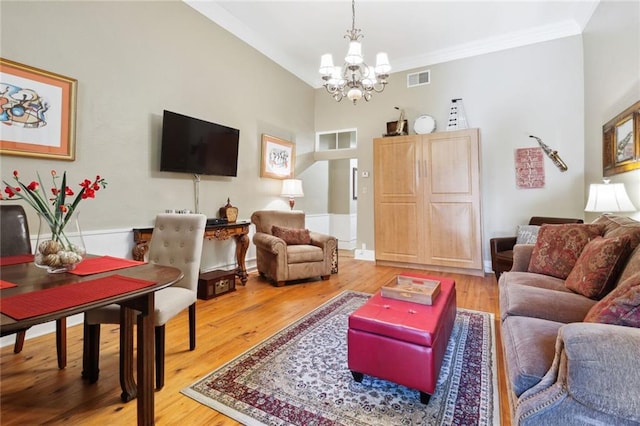 living room featuring an inviting chandelier, crown molding, and light hardwood / wood-style flooring