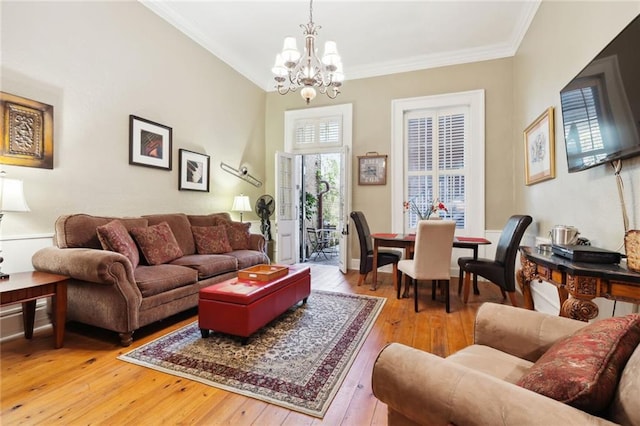 living room with crown molding, a notable chandelier, and light hardwood / wood-style flooring