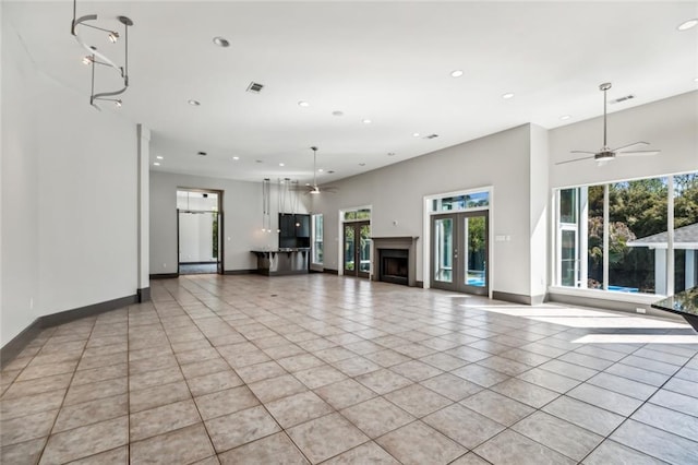 unfurnished living room with ceiling fan and light tile flooring