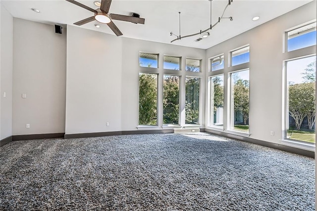 empty room featuring rail lighting, ceiling fan, and carpet