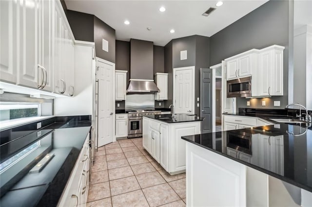 kitchen featuring wall chimney range hood, white cabinetry, appliances with stainless steel finishes, and sink