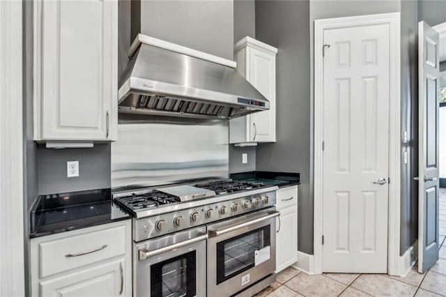 kitchen featuring white cabinetry, double oven range, light tile flooring, and wall chimney exhaust hood