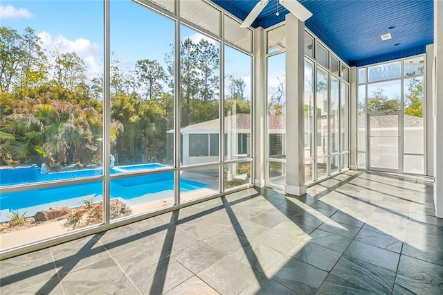 unfurnished sunroom with ceiling fan