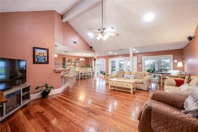 living room featuring ceiling fan, beam ceiling, light hardwood / wood-style floors, and high vaulted ceiling