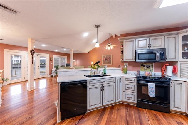 kitchen featuring kitchen peninsula, sink, black appliances, pendant lighting, and lofted ceiling