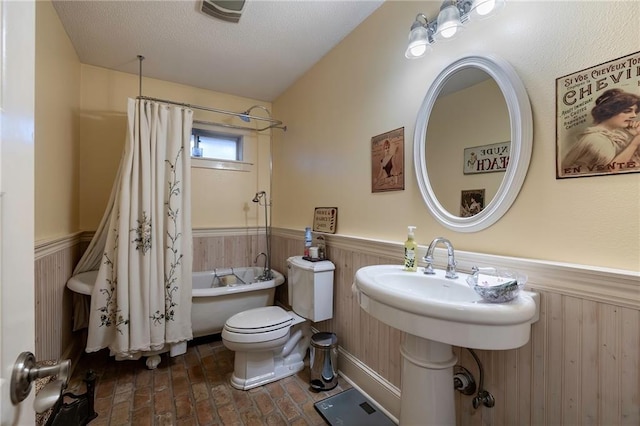 bathroom featuring shower / tub combo, a textured ceiling, toilet, and wooden walls