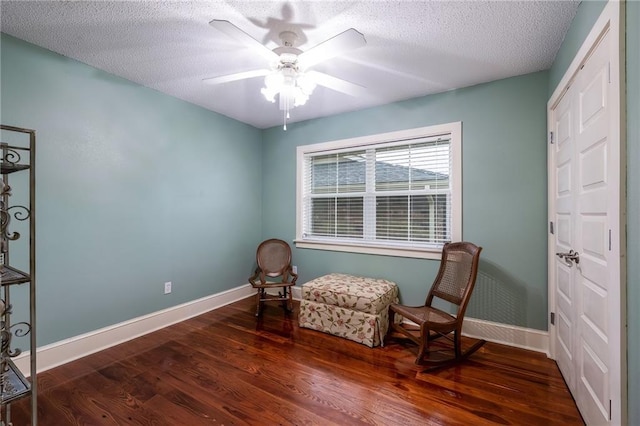 living area with dark hardwood / wood-style floors, ceiling fan, and a textured ceiling