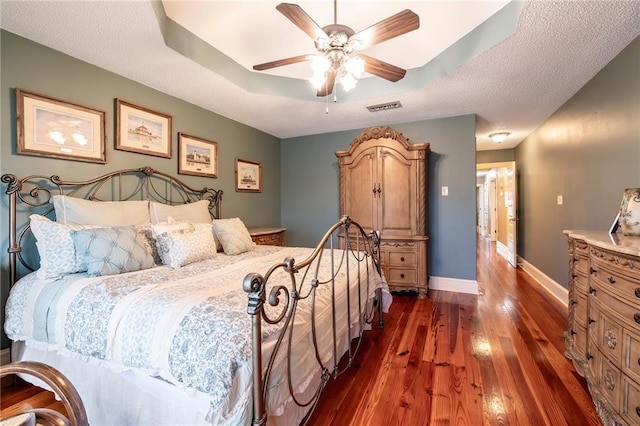 bedroom with a raised ceiling, ceiling fan, and dark hardwood / wood-style floors