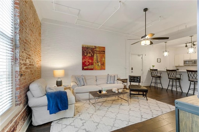 living room with brick wall, a healthy amount of sunlight, ceiling fan, and dark hardwood / wood-style flooring