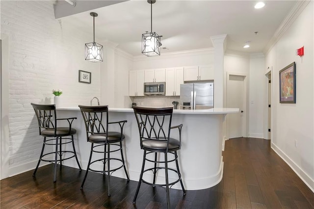 kitchen with backsplash, a breakfast bar area, appliances with stainless steel finishes, and white cabinetry