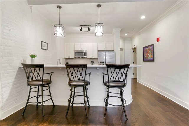 kitchen featuring appliances with stainless steel finishes, white cabinetry, dark wood-type flooring, and a breakfast bar area