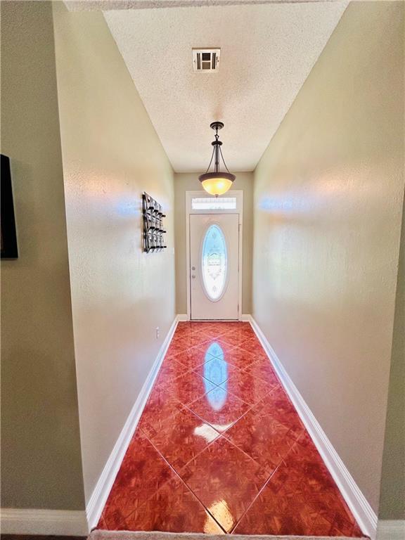 doorway with tile patterned flooring and a textured ceiling