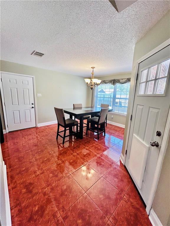 dining room featuring an inviting chandelier, tile patterned flooring, and a textured ceiling