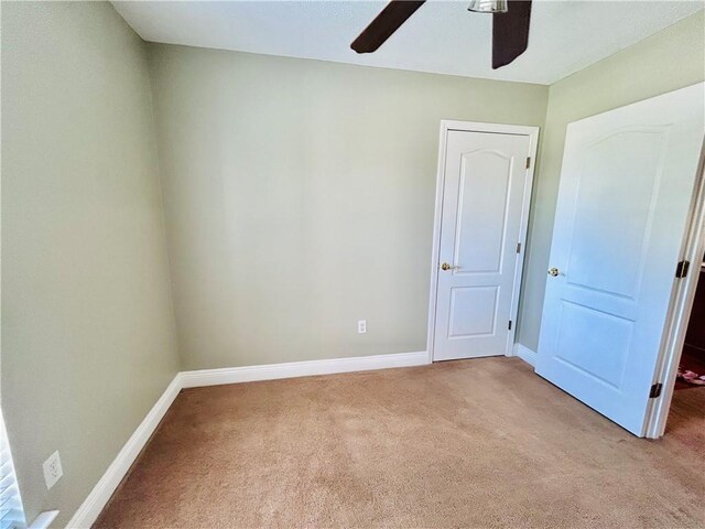 empty room featuring ceiling fan and light carpet