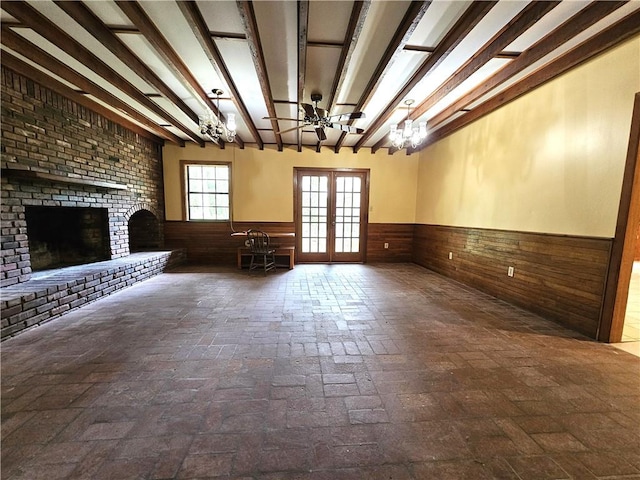 unfurnished living room with a notable chandelier, brick wall, french doors, and a fireplace