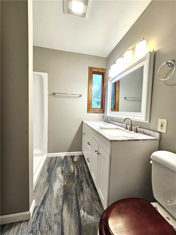 bathroom featuring hardwood / wood-style floors, toilet, and vanity with extensive cabinet space