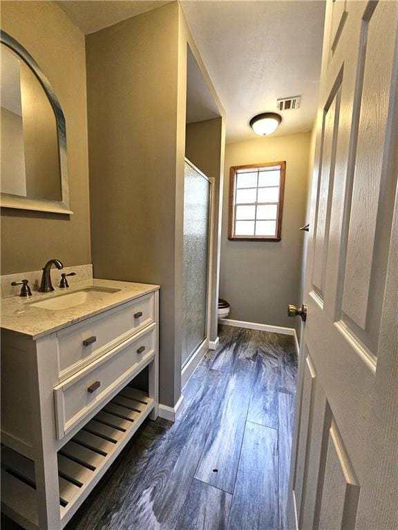 bathroom with walk in shower, vanity, toilet, and hardwood / wood-style flooring