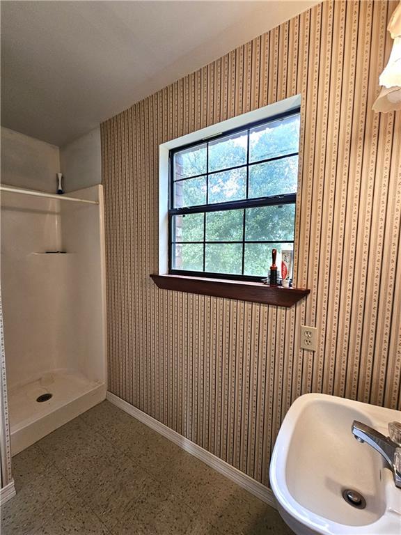 bathroom with tile flooring, a shower, and sink