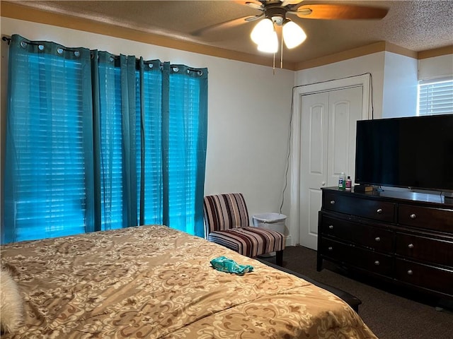 carpeted bedroom featuring ceiling fan and a textured ceiling