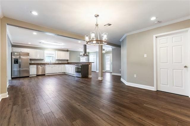 unfurnished living room featuring sink, ornamental molding, dark hardwood / wood-style floors, and an inviting chandelier