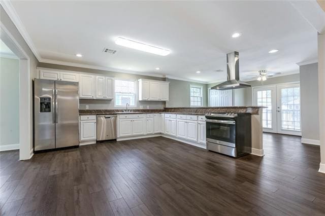 kitchen with ceiling fan, dark hardwood / wood-style flooring, white cabinets, stainless steel appliances, and wall chimney range hood