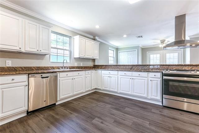 kitchen with ceiling fan, white cabinets, appliances with stainless steel finishes, dark wood-type flooring, and wall chimney exhaust hood