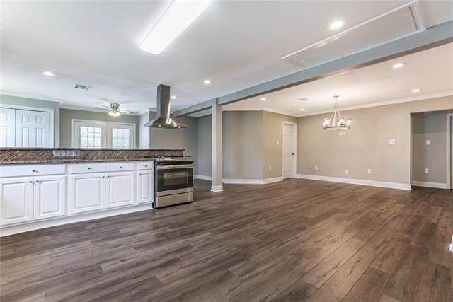 kitchen featuring stainless steel stove, white cabinets, dark hardwood / wood-style flooring, and wall chimney range hood