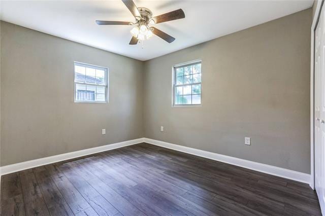 empty room with ceiling fan, dark hardwood / wood-style floors, and a healthy amount of sunlight