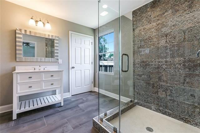 bathroom with a shower with shower door and large vanity