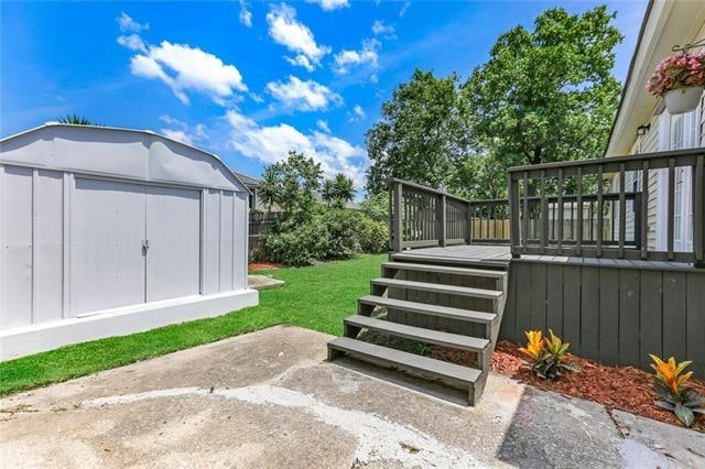 view of yard with a deck, a patio, and a storage unit