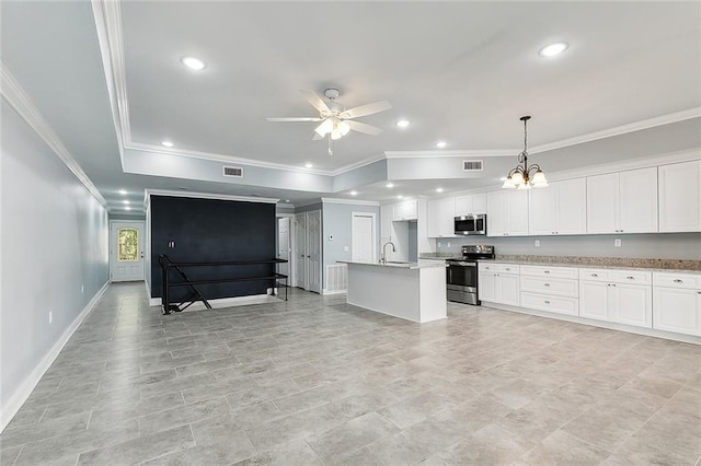 interior space featuring ceiling fan with notable chandelier, a center island with sink, appliances with stainless steel finishes, white cabinets, and hanging light fixtures