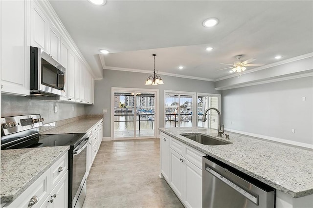 kitchen with ceiling fan with notable chandelier, appliances with stainless steel finishes, sink, white cabinets, and pendant lighting