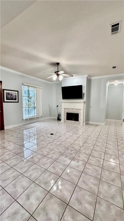 unfurnished living room with light tile floors, ornamental molding, ceiling fan, and a tile fireplace