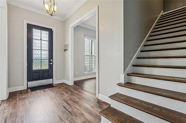 entrance foyer with dark wood-type flooring, an inviting chandelier, and crown molding