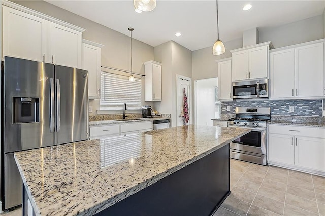 kitchen with backsplash, white cabinets, sink, appliances with stainless steel finishes, and decorative light fixtures