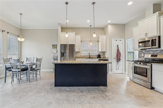 kitchen with backsplash, stainless steel appliances, white cabinets, a center island, and hanging light fixtures