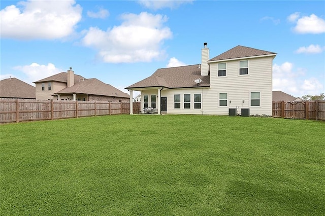 rear view of property featuring central AC unit and a yard