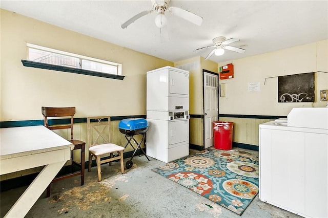 laundry room with wood walls, stacked washer and dryer, and ceiling fan